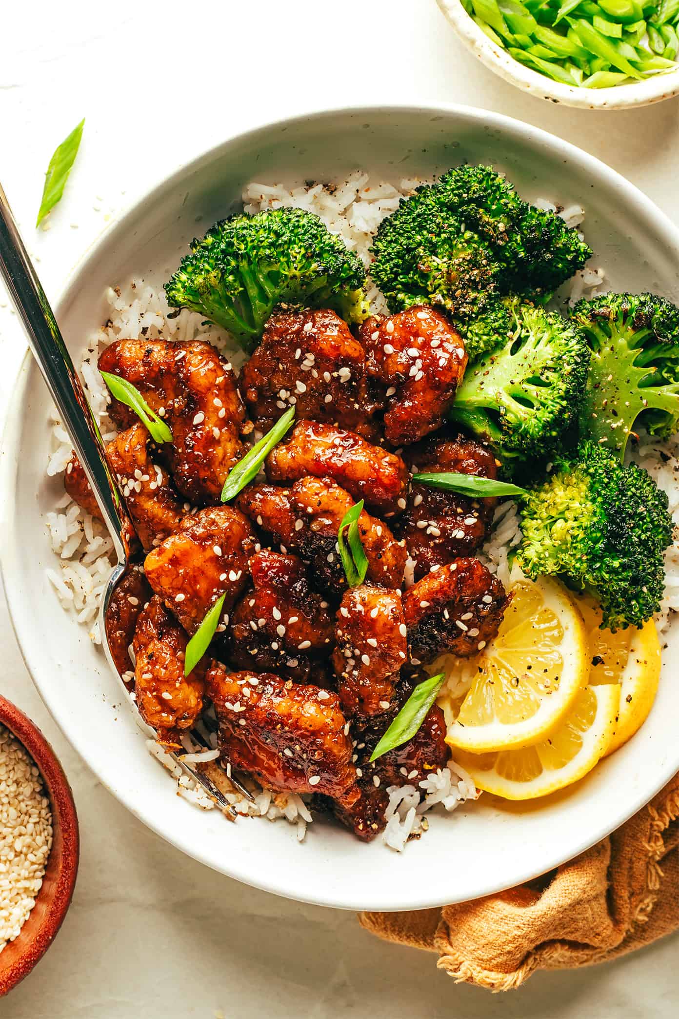 Sticky honey lemon chicken in bowl with roasted broccoli rice and lemon